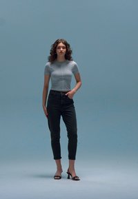 Gray short-sleeve top with a fitted silhouette, paired with dark jeans and black heeled sandals. Simple design, smooth fabric, and neutral colors.