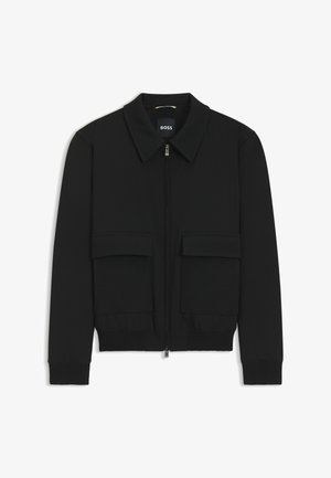 Black bomber jacket with a collared neck, zip front, and two large flap pockets. Features ribbed cuffs and hem, made of textured fabric.