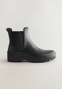 Schwarzer Gummistiefel bis zum Knöchel mit strukturierten Seitenpaneelen, Zugschlaufe und robuster Sohle mit tiefem Profil für besseren Halt. Glatte Oberflächenbeschaffenheit.