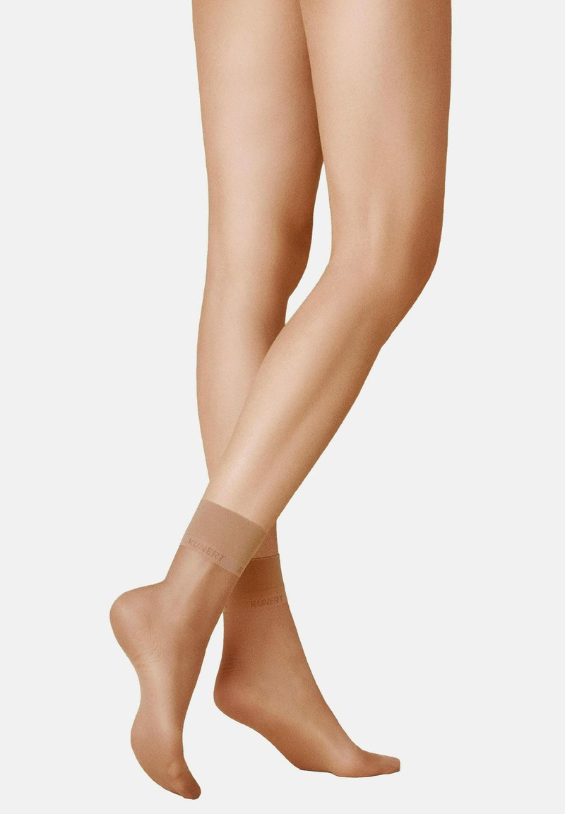 Nackte Knöchel-Socken mit einer glatten, transparenten Textur und einer verstärkten Spitze. Das elastische Band ist mit dem Markennamen "Kunert" bedruckt.