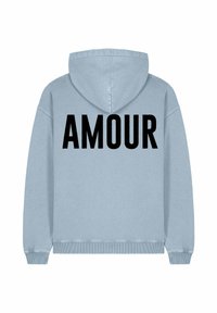 Pale blue kapucnis pulóver, amelynek hátulján nagy fekete "AMOUR" felirat található. Puha anyagból készült, laza fazonú, és állítható kapucnival rendelkezik.