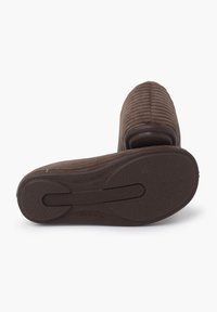 Chausson marron à côtes avec une tige en textile douce. La semelle en caoutchouc présente une texture antidérapante et un design moulé pour le confort et le soutien.