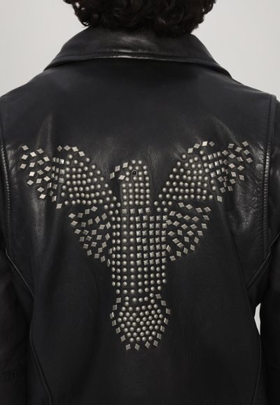 Svart läderjacka med en naglad örn-design på ryggen. Har silverfärgade runda och fyrkantiga nitar i en strukturerad uppställning.