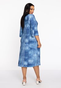 Blaues Jeanskleid aus leichtem Stoff, mit 3/4-Bellärmeln, geradem Schnitt und vertikalen Nahtdetails. Abgerundeter Saum und Rückansicht gezeigt.