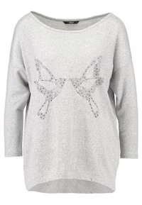 Haut gris à manches longues, coupe ample, avec un motif papillon distinctif composé de petits strass au centre.