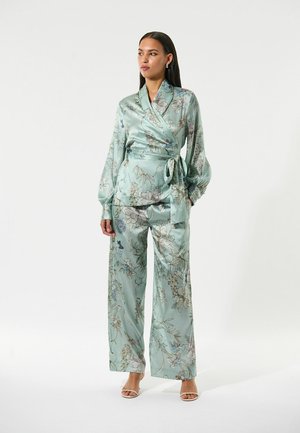 Helle türkisfarbene Satin-Hosen mit weitem Bein und Wickeloberteil mit floralem Muster, das lange Ärmel, eine Bindegürtel und eine glänzende Textur aufweist.