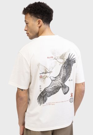 Crème katoenen t-shirt met een grote zwarte vogelafbeelding op de achterkant, verfraaid met rode tekst en geometrische vormen. Korte mouwen, ontspannen pasvorm.