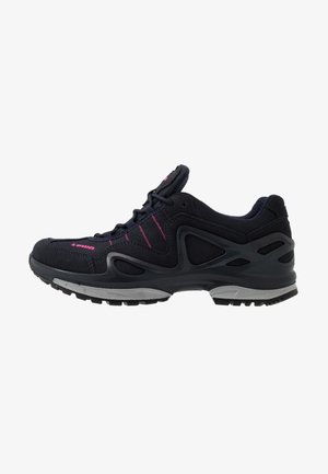 Black athletic shoe with pink accents, textured fabric upper, cushioned sole, and a supportive design featuring cutouts on the sides.