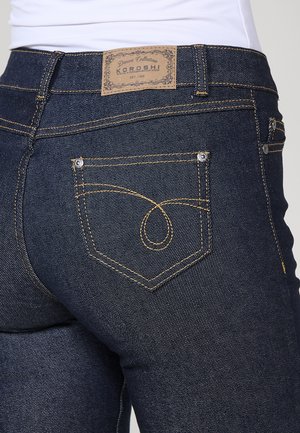 I jeans in denim scuro presentano una vestibilità classica con vita alta, cuciture gialle a contrasto e un design distintivo delle tasche posteriori.