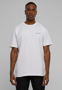 Weißes Baumwoll-T-Shirt mit Rundhalsausschnitt und kurzen Ärmeln, ausgestattet mit einem kleinen blauen gestickten Logo auf der linken Brust. Einfaches Design, normaler Schnitt.