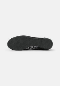 Scarpa nera con tomaia in pizzo testurizzato e suola in gomma flessibile a motivo. Punta tondeggiante e design senza cuciture per un aspetto elegante.