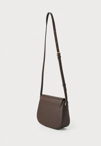Sac bandoulière en cuir marron avec une forme incurvée, une bandoulière réglable et une fermeture à rabat. Il présente une texture lisse et des accessoires en ton doré.