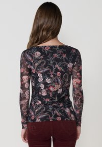 Camiseta de manga larga negra con estampado floral y de paisley, con un escote en forma de bote y un corte ajustado. Fabricada en un material ligero y translúcido.