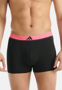 Svarta boxershorts med en rosa midjeband som har Adidas-logotypen i svart. Designen inkluderar en åtsittande passform och en slät textur.