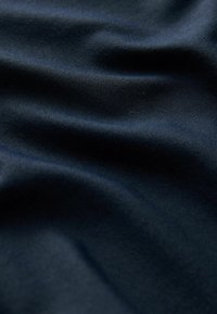 Dark navy fabric with a smooth, slightly reflective texture, displaying soft drapes and subtle, fine woven pattern throughout.