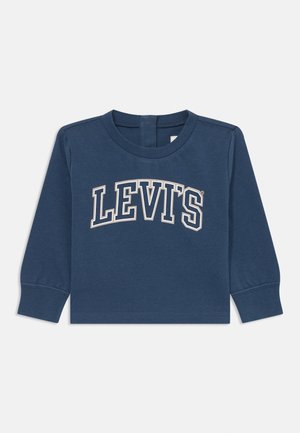 Marineblå langærmet skjorte med rund hals og "LEVI'S" trykt i store hvide og beige bogstaver tværs over brystet.