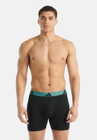 Czarne bokserki z elastycznym turkusowym pasem w talii z czarnymi logo adidas, zapewniając dopasowanie i gładką teksturę.