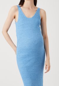 Abito a maglia azzurro chiaro, con lavorazione a coste e design senza maniche, presenta una scollatura a V e una silhouette aderente. Tessuto morbido e strutturato.