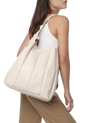 Sac fourre-tout beige avec un design plissé texturé en matériau synthétique lisse. Dispose d'une bandoulière réglable et d'un accent en métal argenté.