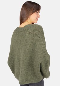 Olivegrüner, übergroßer Strickpullover mit weitem Bootsausschnitt, strukturiertem Oberflächen und überschnittenen Schultern, von hinten gezeigt.