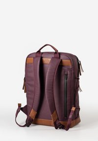 Zaino di un intenso bordeaux scuro con dettagli in pelle color tan. Presenta due spallacci imbottiti, una maniglia superiore e una tasca frontale con cerniera.