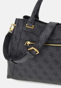 Czarna torebka z materiału z teksturowanym wzorem, zdobiona złotymi akcentami, z kieszenią na zamek błyskawiczny oraz odpinanym, regulowanym paskiem.