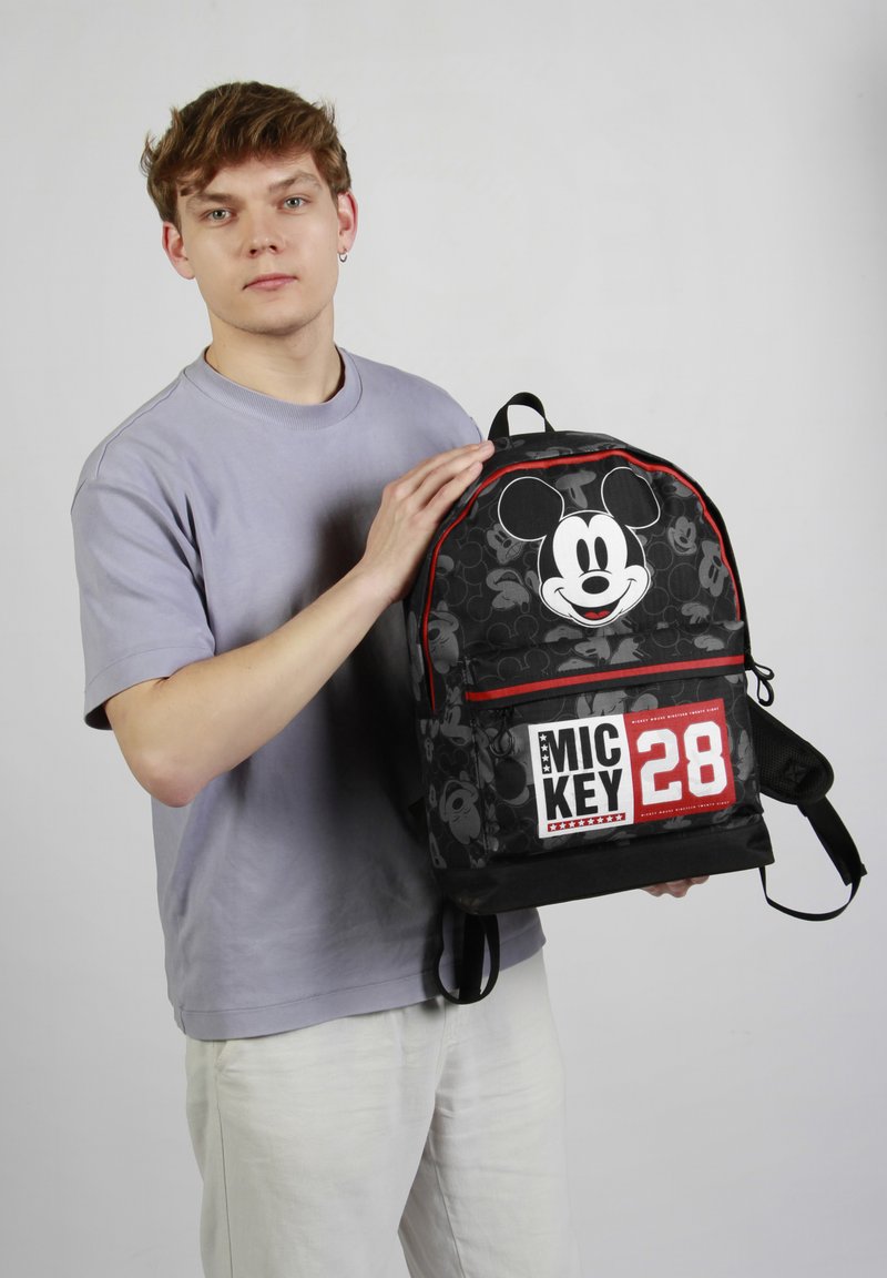 Mochila negra con un gran gráfico de Mickey Mouse, acentos rojos y el texto "MIC KEY 28" en la parte frontal, con correas dobles para los hombros.