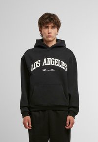 Czarna bluza z kapturem z dużym nadrukiem "LOS ANGELES" w kolorze białym. Posiada kieszeń kangurką oraz regulowany kaptur ze sznurkiem. Miękka faktura.