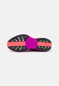 Nike løbesko sål i livlig pink og sort, med teksturerede mønstre, en stor flad bund og et synligt mærkenavn på hælen.