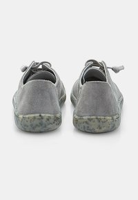 Pantofi casual gri din suede, cu tălpi din cauciuc cu pete, prezentați din partea tocului, cu șireturile legate înnodate în spate.