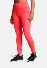 Roosa kõrge vöökoha ja tekstuuriga kangaga leggings, millel on küljetaskud. Kombineeritud mustade sportlike kingadega, millel on valge tall ja paelad.