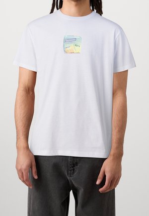 Bílé bavlněné tričko s barevným motivem šťávového krabičky a nápisem "Cleptomanicx". Krátké rukávy a volný střih.