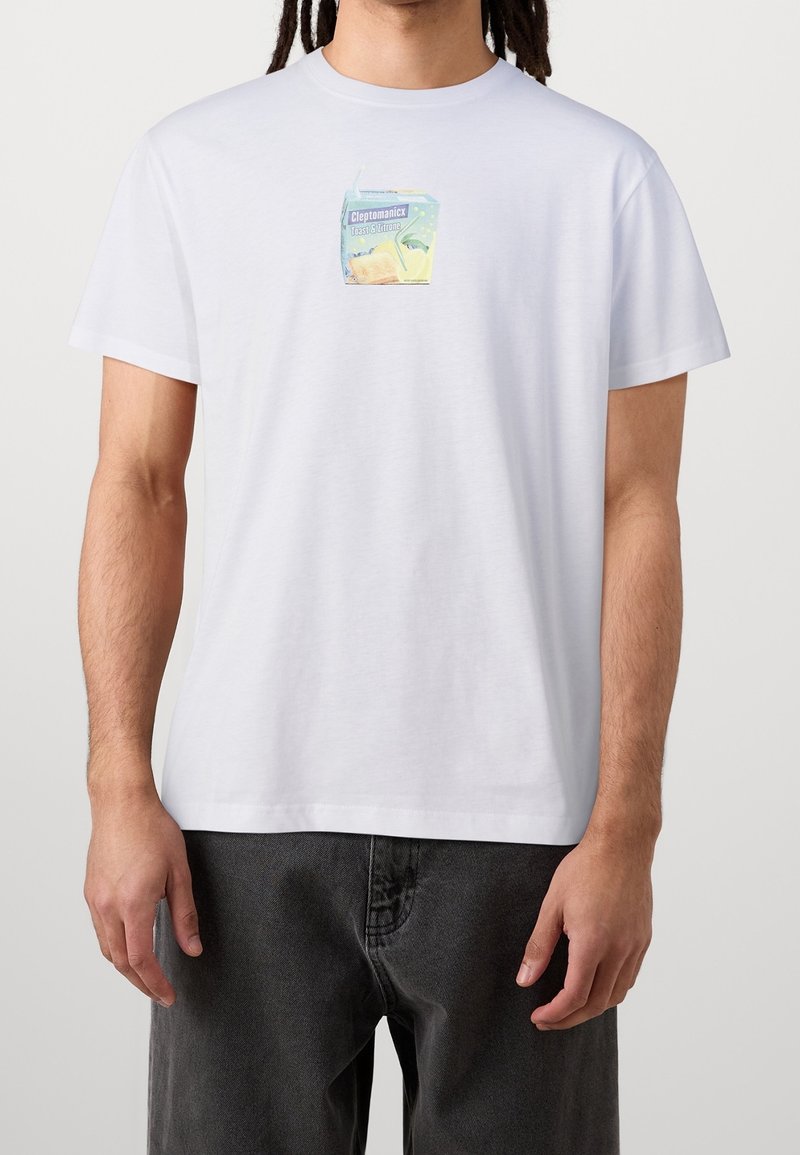 Valkoinen puuvillainen t-paita, jossa on värikäs kuva mehupaketista ja teksti "Cleptomanicx". Lyhyet hihat ja rento istuvuus.