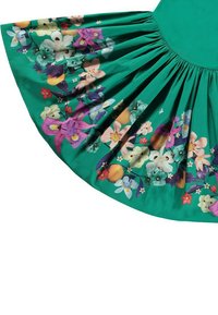 Grön kjol med veck och ett blommigt kantmönster med lila, rosa, vita, blå blommor, gröna blad och orange frukter.