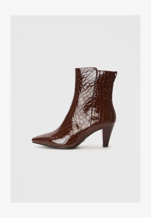 Bottines marron avec une finition brillante en texture crocodile. Présentent un bout pointu et un talon conique de hauteur moyenne.
