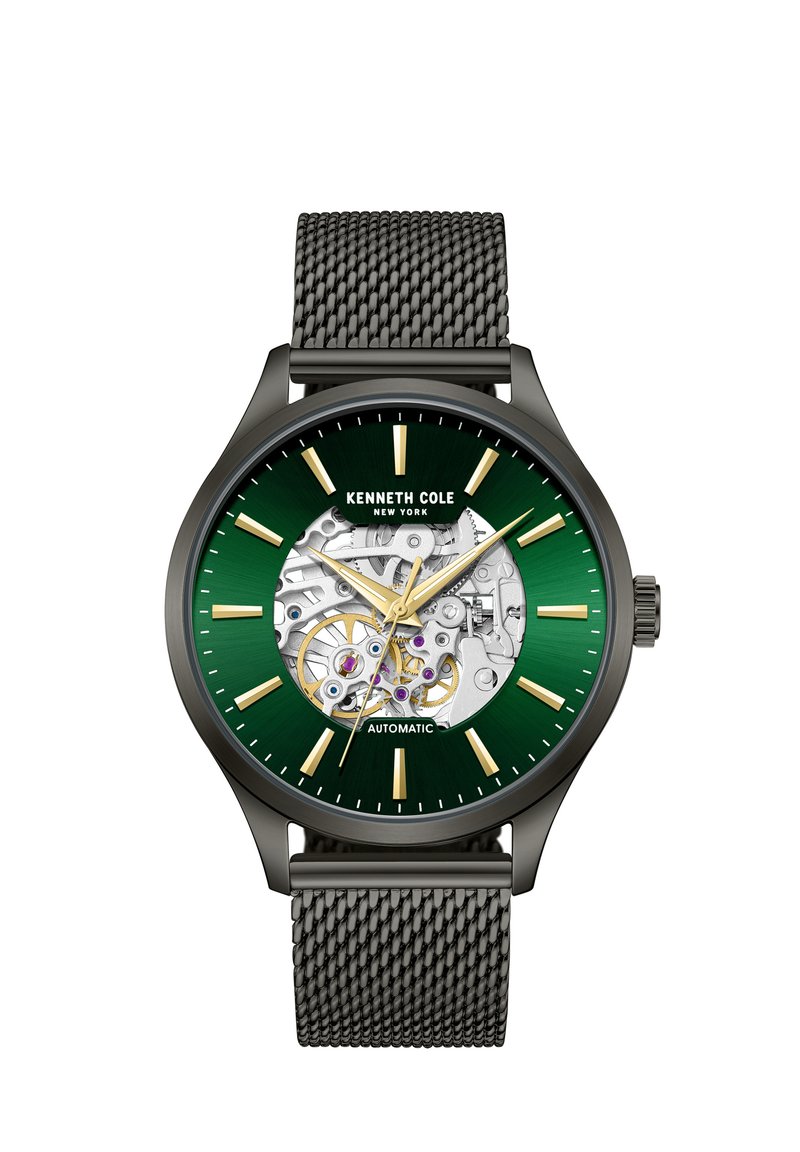 Automatische Uhr mit grünem Ziffernblatt, goldenen Stundenmarkierungen und transparentem Gehäuseboden. Schwarzes Metall-Mesh-Armband und runder Gehäuse aus rostfreiem Stahl.
