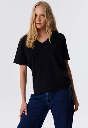 Zwarte V-hals t-shirt van zachte stof, met korte mouwen en een relaxte pasvorm. Draag het met blauwe denim jeans.