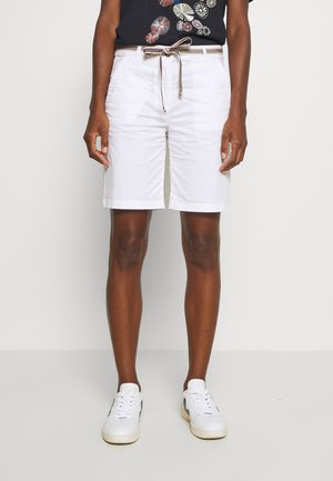 Weiße Baumwollshorts mit einem Kordelzugbund, ausgestattet mit Seitentaschen und einer glatten Textur. Kombiniert mit weißen Turnschuhen und einem dunkelgrauen T-Shirt mit Grafik.