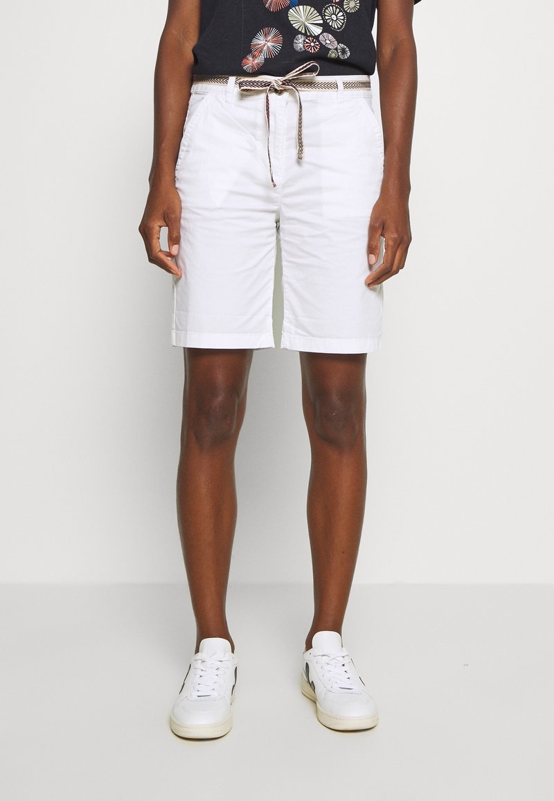 Hvide bomulds shorts med snøre i taljen, med sidelommer og en glat tekstur. Kombinationen inkluderer hvide sneakers og en mørk grafisk t-shirt.