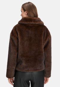 Brun faux fur jakke med høj krave, struktureret finish og afslappet pasform. Ærmerne er lange og lidt oversized.