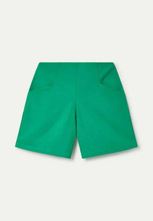 Pantalones cortos verdes de talle alto con bolsillos inclinados delanteros, ajuste entallado y longitud hasta la mitad del muslo sobre un fondo claro