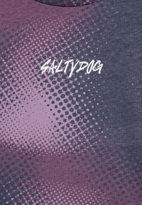 Grafické tričko s gradientním designem obsahující fialové a šedé tečky. Text "SALTYDOG" bílou barvou ve středu, styl s kulatým výstřihem.