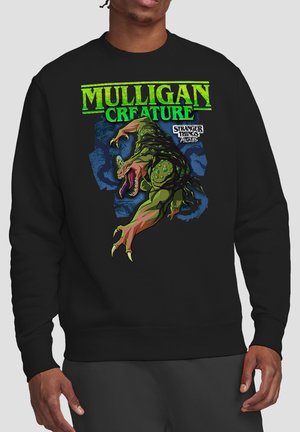 Black sweatshirt with green text "Mulligan Creature" and graphic of a green, clawed monster from Stranger Things: Tales 85.