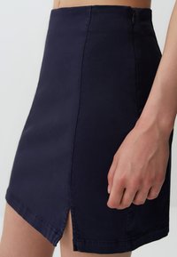 Gonna mini blu navy con una texture morbida, dotata di uno spacco laterale e una cerniera nascosta sul retro per la chiusura.