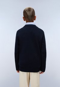 Pull en maille navy avec un col et un ourlet côtelés, doté de manches longues et d'un tissu texturé. Col de chemise blanc visible en dessous.