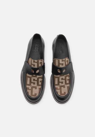 Chaussures noires en cuir avec des panneaux en tissu à motifs marron, dotées d'une sangle avec un détail découpé. Logo embossé sur la semelle intérieure.