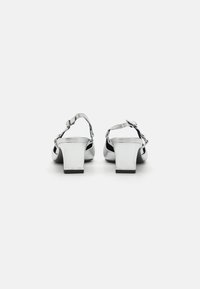 Strieborné metalické sandále na opätku s členkovými remienkami, blokovými opätkami a textúrovaným povrchom. Obsahujú hladkú podrážku a moderný minimalistický dizajn.