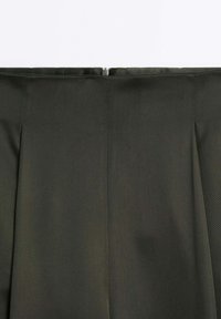 Ciemnozielona, plisowana spódnica o gładkiej fakturze, z ukrytym zamkiem błyskawicznym z tyłu i starannie wykończonymi szwami.