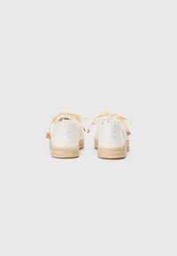 Hvite canvas espadriller med såle av jutevev, frynsete detaljer og lys beige snøring. Subtilt tekstillogo på hælen.
