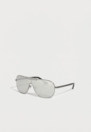 Lentäjätyyliset aurinkolasit hopeisilla heijastavilla linsseillä ja ohuilla mustilla sankoilla, joissa on kaiverrettuja geometrisia kuvioita.